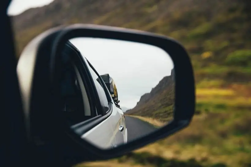 Una carretera abierta reflejada en el espejo lateral de un auto